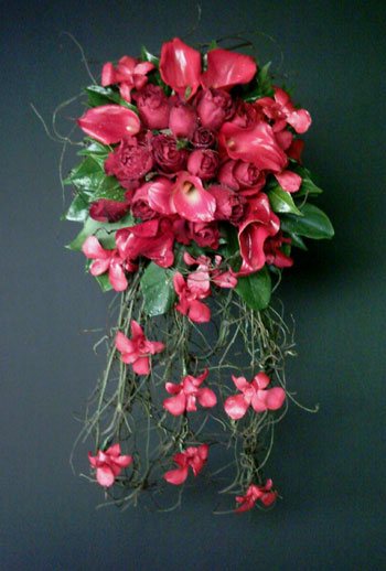 Cascading pastel red bouquet made of roses call lilies and orchids