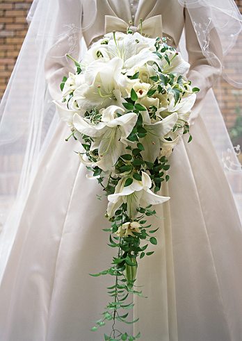 Cascading bridal bouquet with white lilies and green leaves