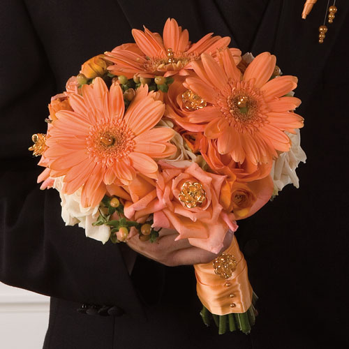 Orange Gerberas berries and orange roses in this hand tied bouquet tied 