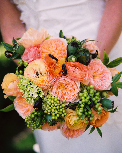 Large orange colored Ranunculus and green berries make up the bulk of this