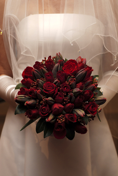 Red berries red roses and dark red tulips make up this exquisite bridal 