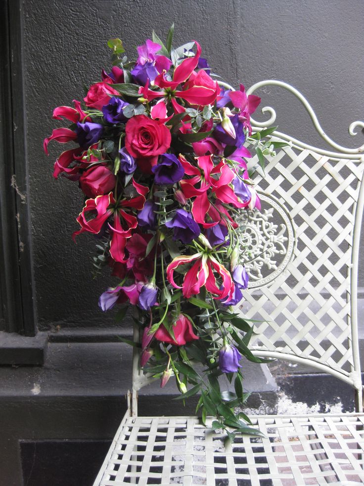 Bride's cascade bouquet of gloriosa lilies, lisianthus, roses, dendrobium orchids and ruscus